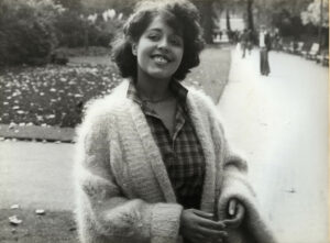 Poly Styrene in a park wearing a plaid shirt and cardigan