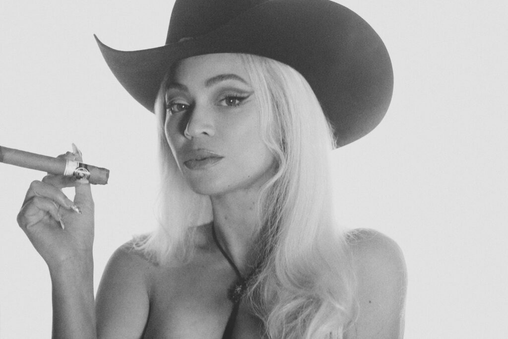 B&W photo of Beyonce in cowboy hat and smoking cigar.