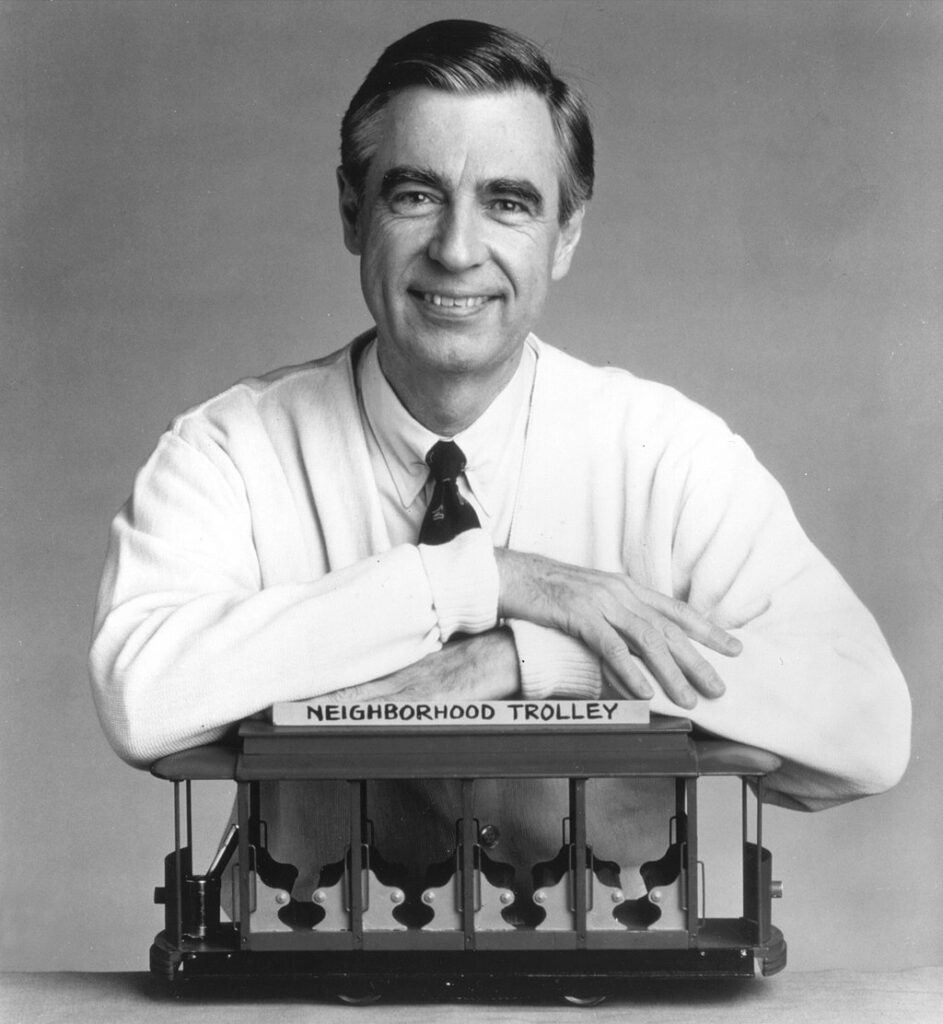 Mister Rogers leaning over his toy trolley