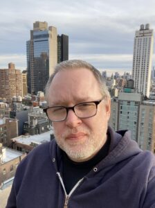 Jeremy in glasses and a beard in an urban rooftop