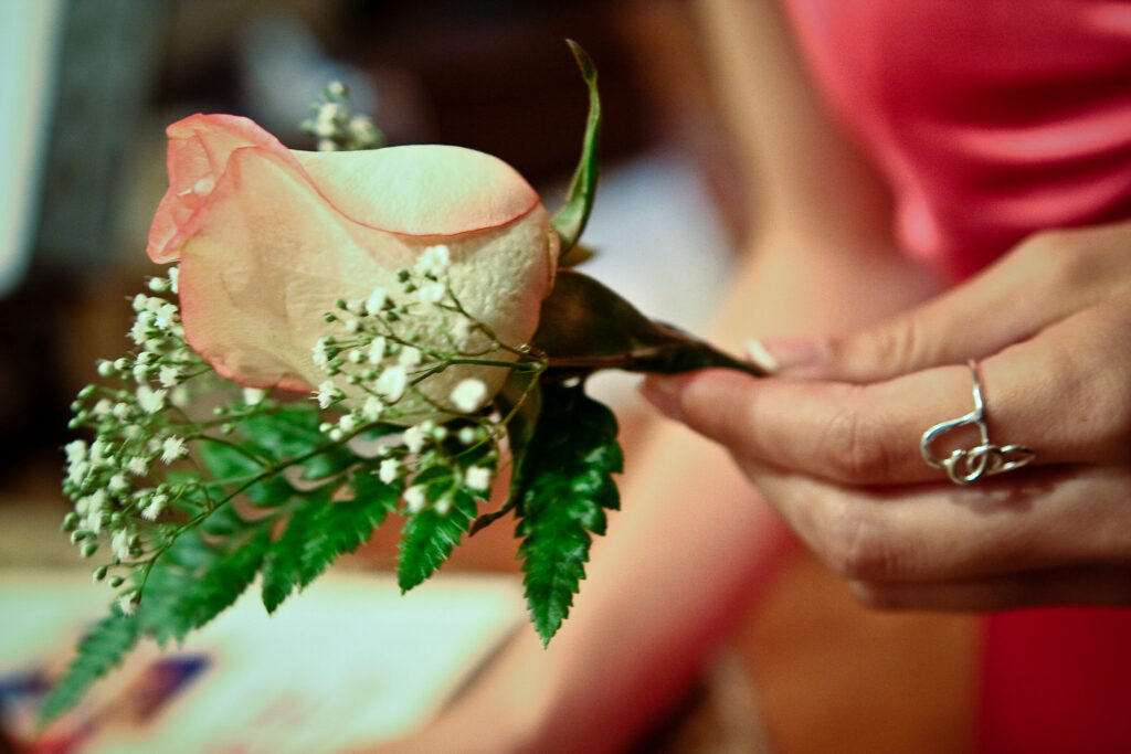 close up of woman's hand holding a rose with baby's breath.