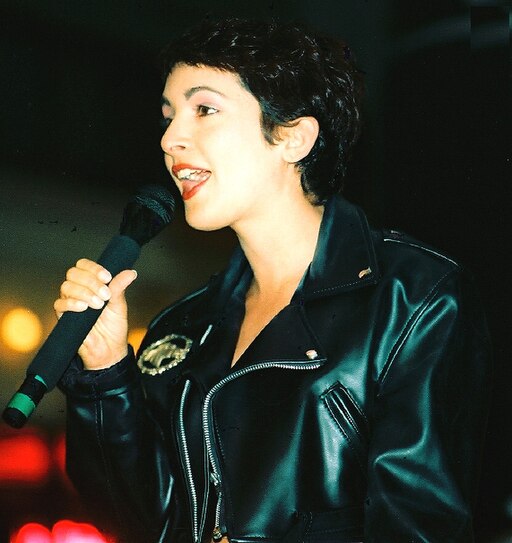 Jane Wiedlin in black leather jacket singin into a microphone