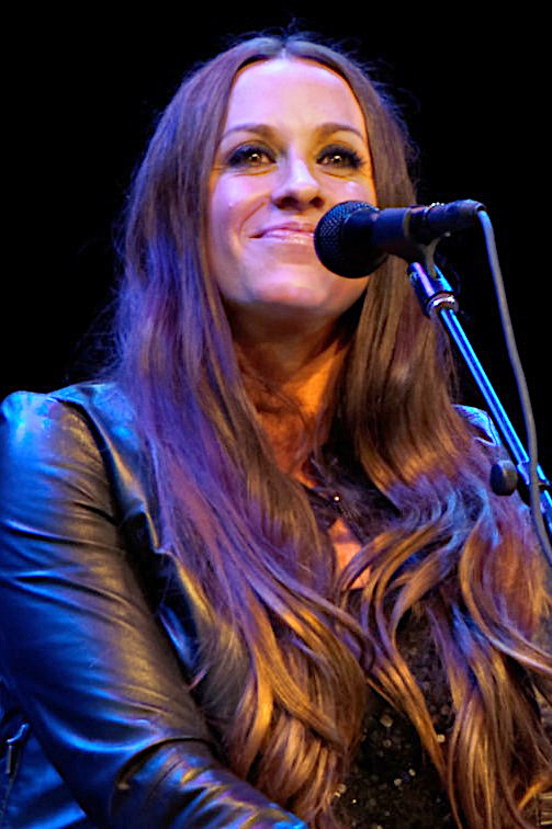 Alanis Morrisette smiling behind a microphone