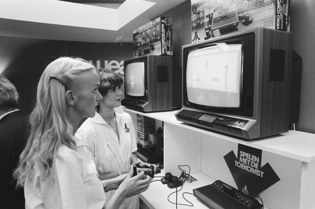 Black and white photo of 2 women in German store playing an atari game console