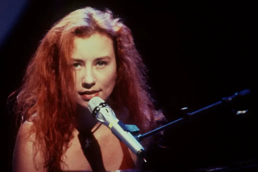 Tori Amos with curly res hair singing into a mic