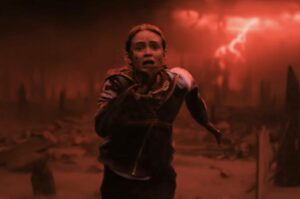 Max (played by Sadie Sink) running for her life with the red and dark upside down world behind her