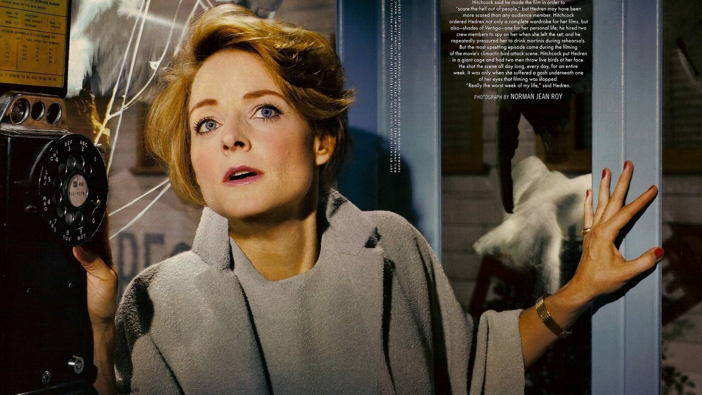 Jodie Foster Looking u by an antique payphone in a dramatic pose wearing a wool suit