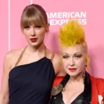 Taylor Swift in black dress next to Cyndi Lauper in a red jacket and black dress