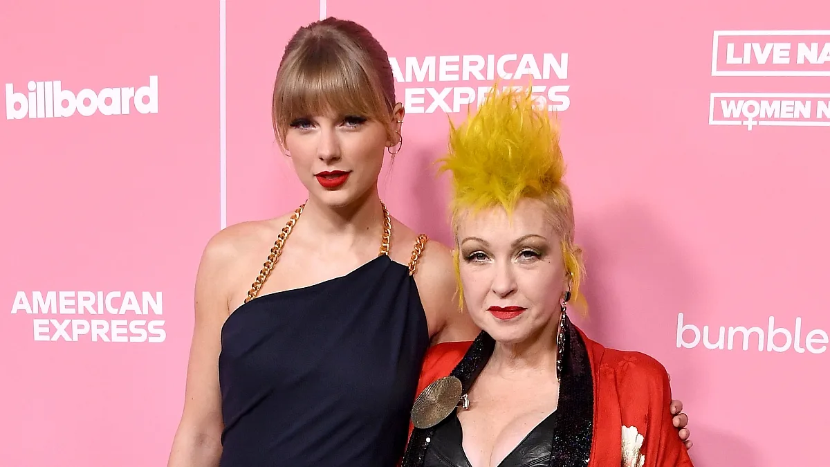 Taylor Swift in black dress next to Cyndi Lauper in a red jacket and black dress