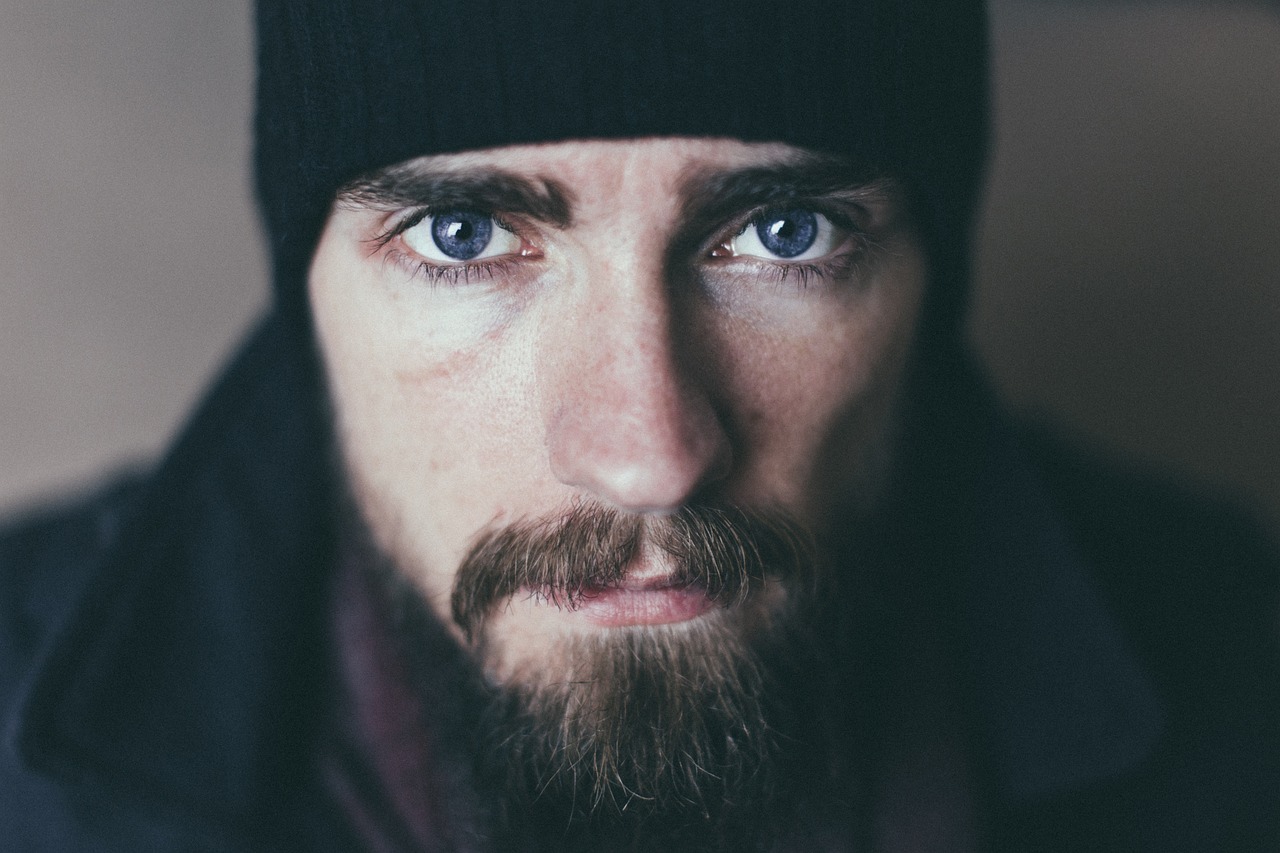 Man staring intensely wearing a black hat and has a beard