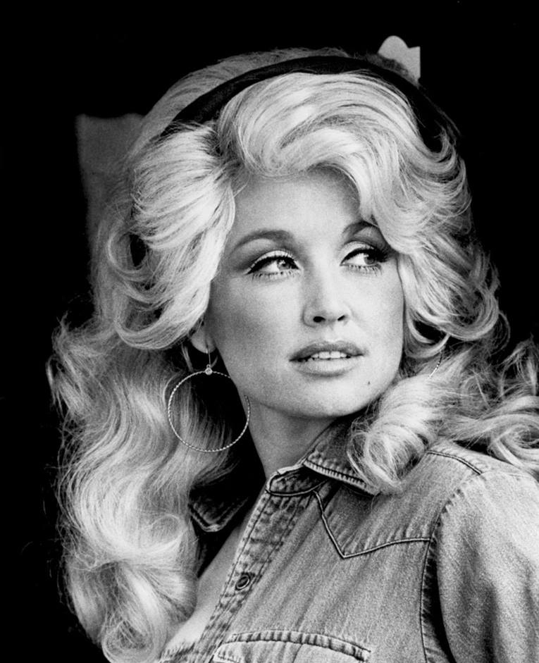 Young Dolly Parton in denim shirt with long blonde hair. Black and white photo