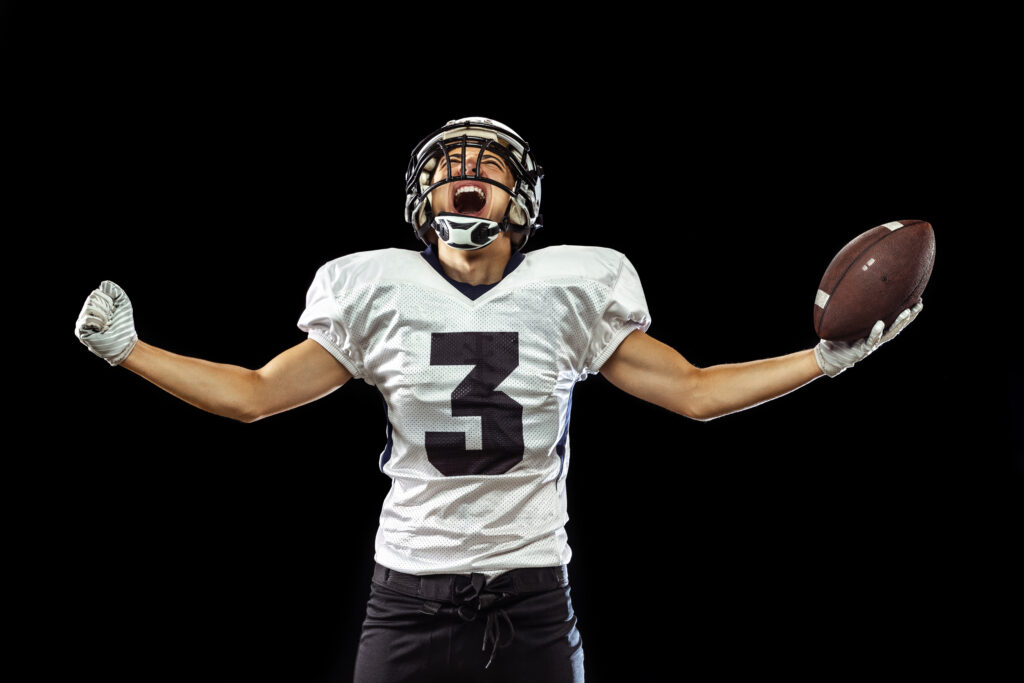 portrait of American football player in sports equipment isolated on dark studio background.