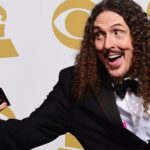 Weird Al in a Tuxedo smiling while holding a grammy award