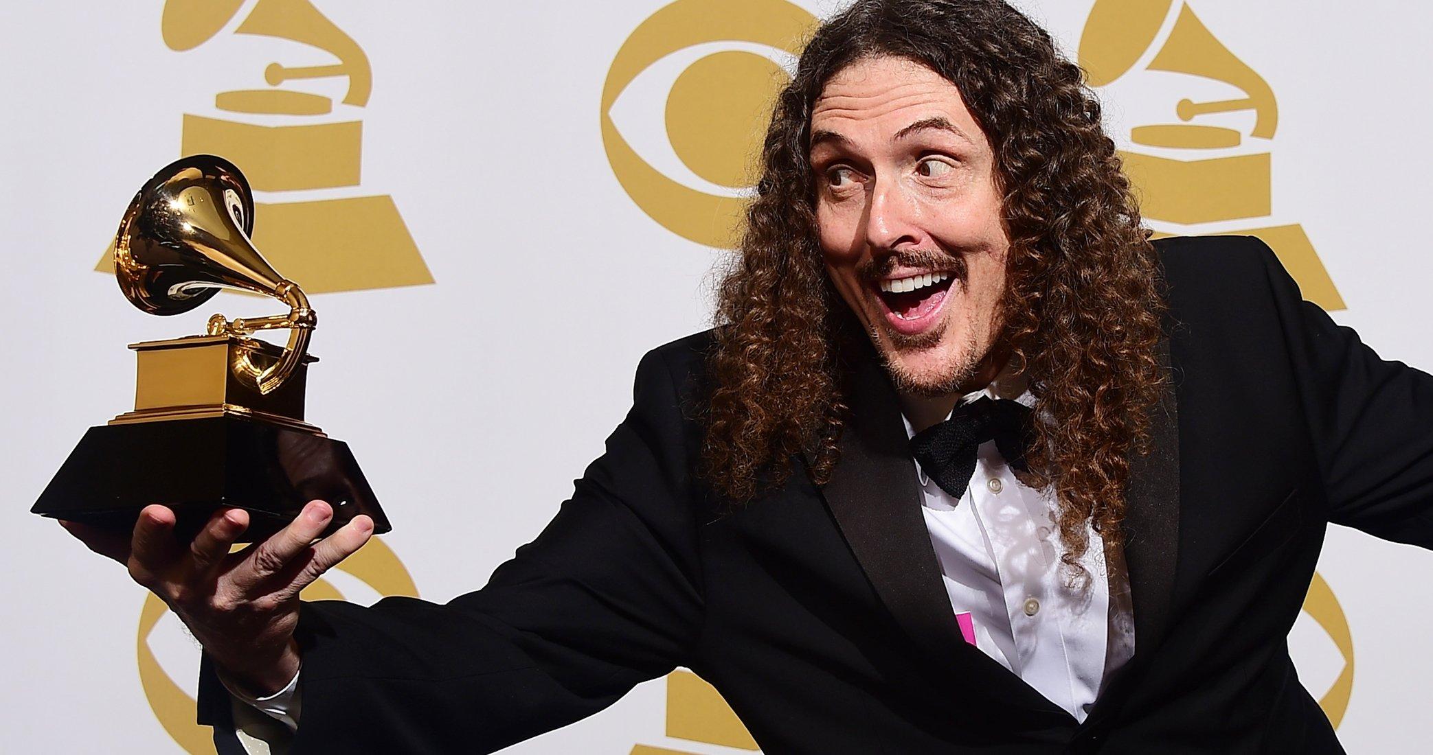 Weird Al in a Tuxedo smiling while holding a grammy award