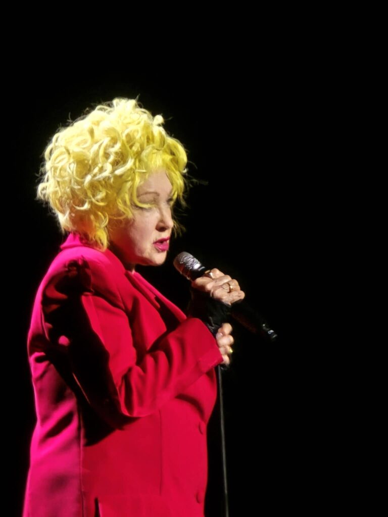 Cybdi Lauper in a red dress singing