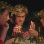 George Michael at a Christmas table looking into the camera.