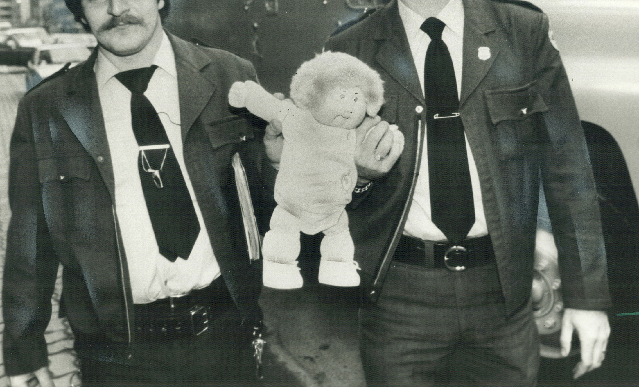 Cabbage Patch doll carried away by 2 police officers