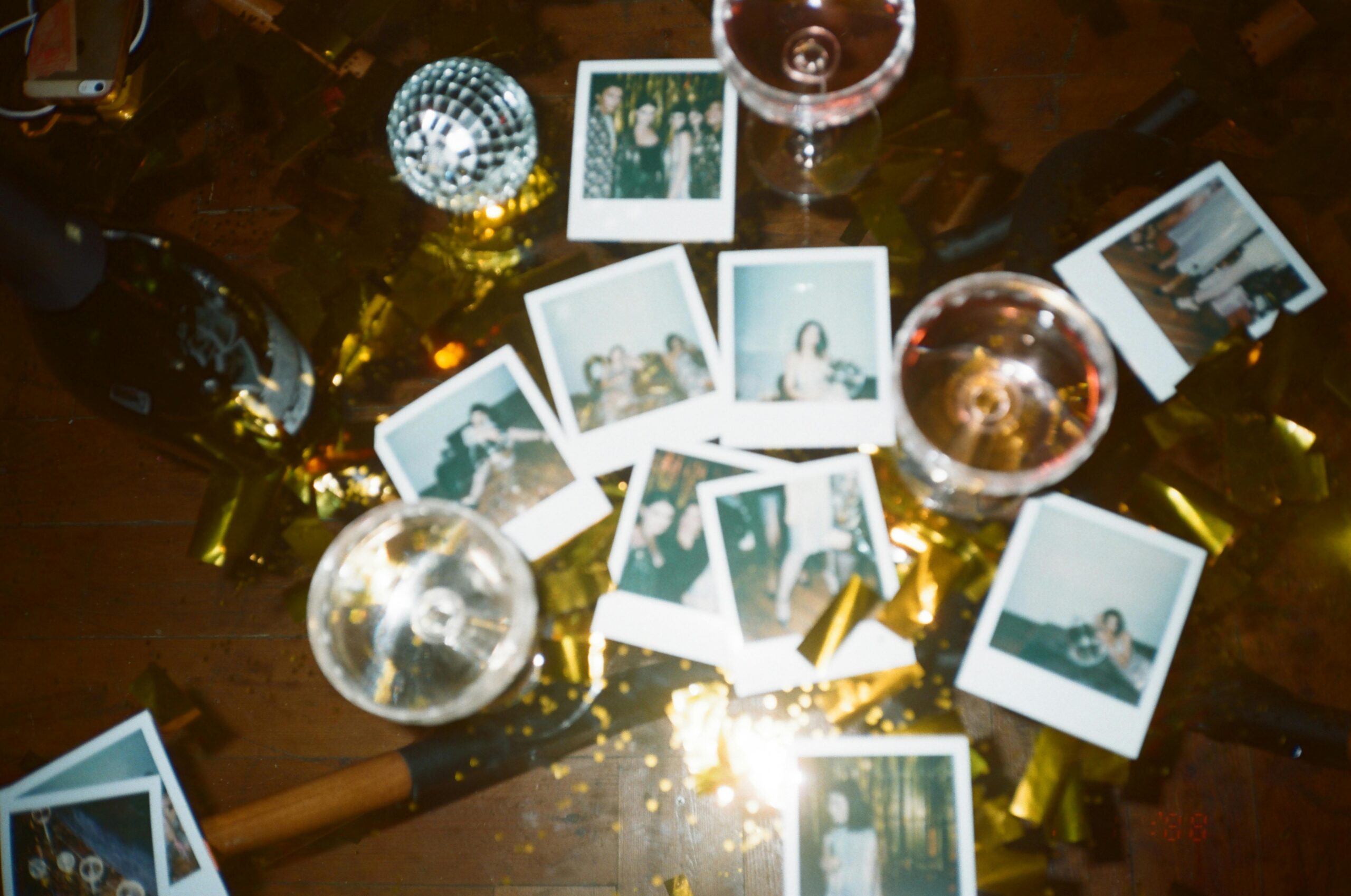 A nostalgic collection of instant photos amidst a festive party scene with wine glasses and disco decor.