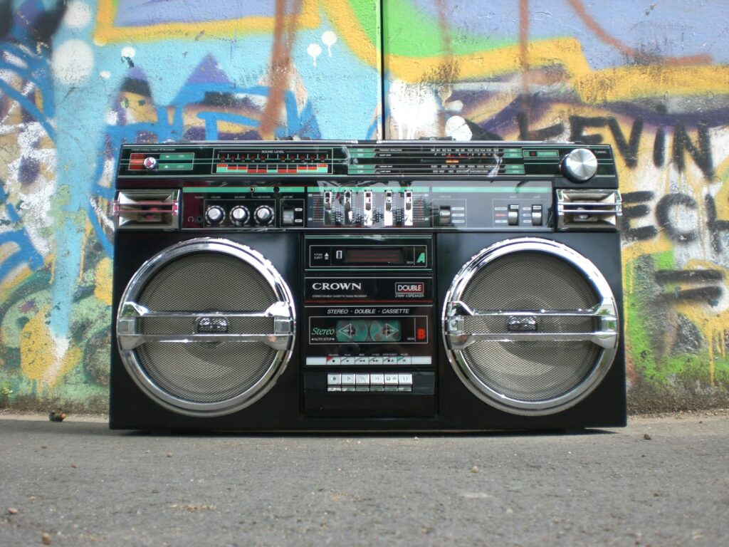 Classic vintage boombox placed in front of a vibrant graffiti-covered wall. Perfect for retro lovers.