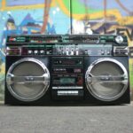 Classic vintage boombox placed in front of a vibrant graffiti-covered wall. Perfect for retro lovers.