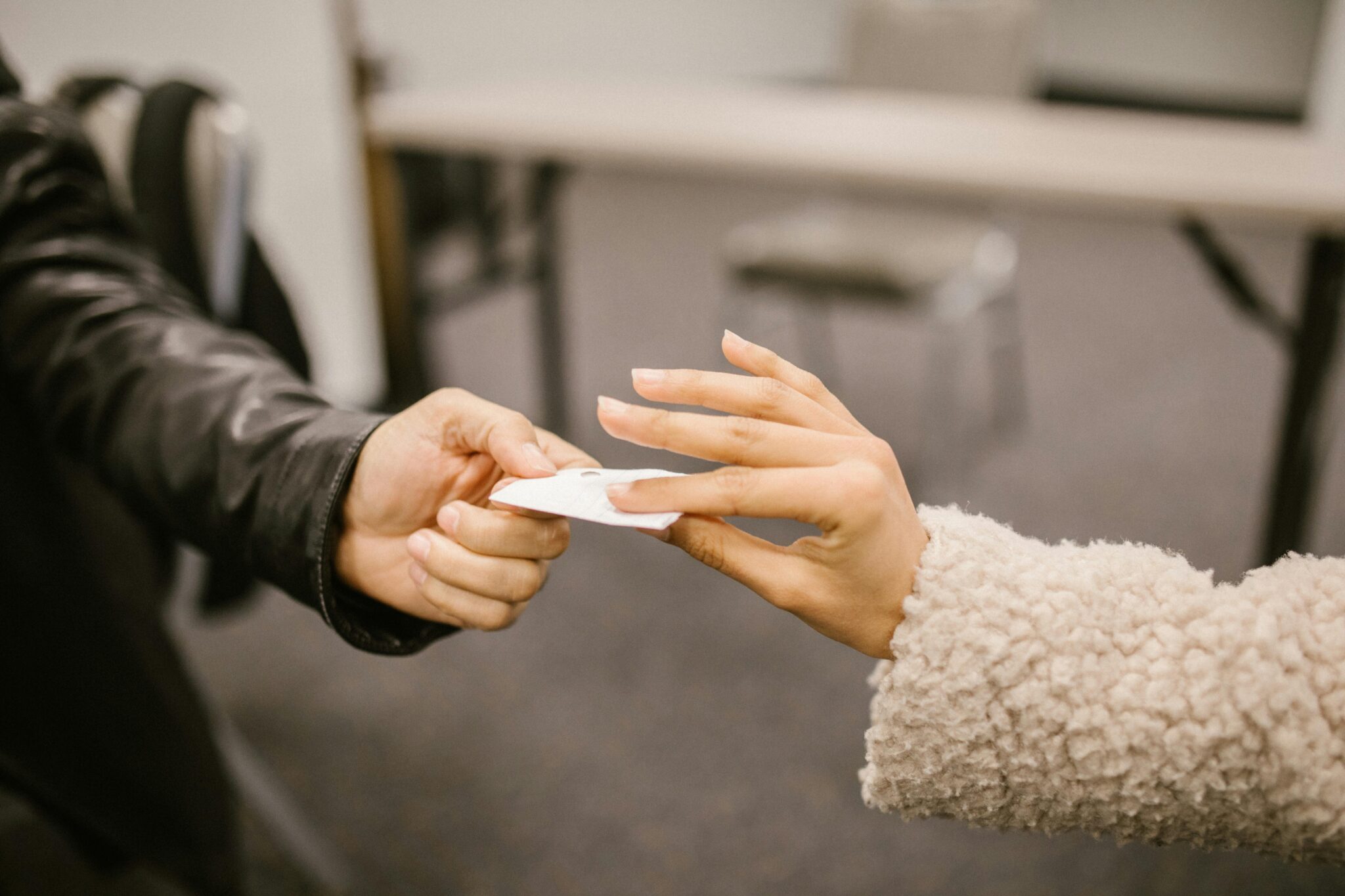 Close-up of two people exchanging a note, hinting at secretive communication.