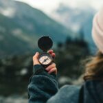 A woman holds a compass in the Canadian mountains, symbolizing adventure and exploration.