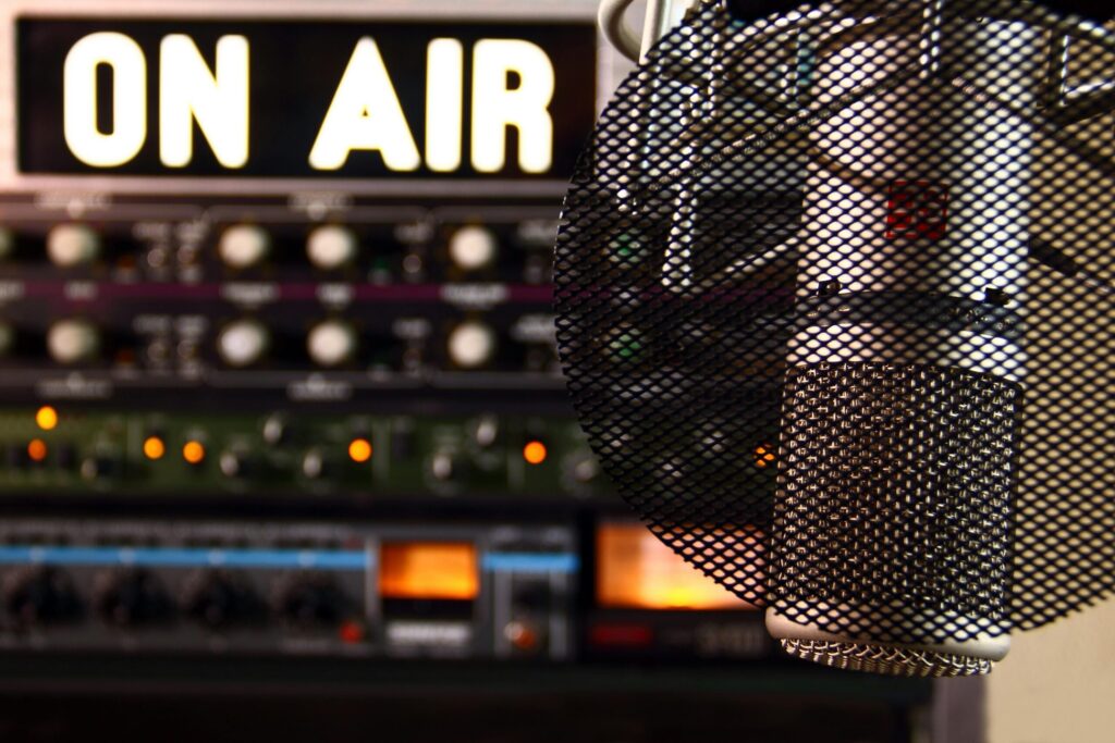 Close-up of a radio microphone and control panel in an illuminated studio.